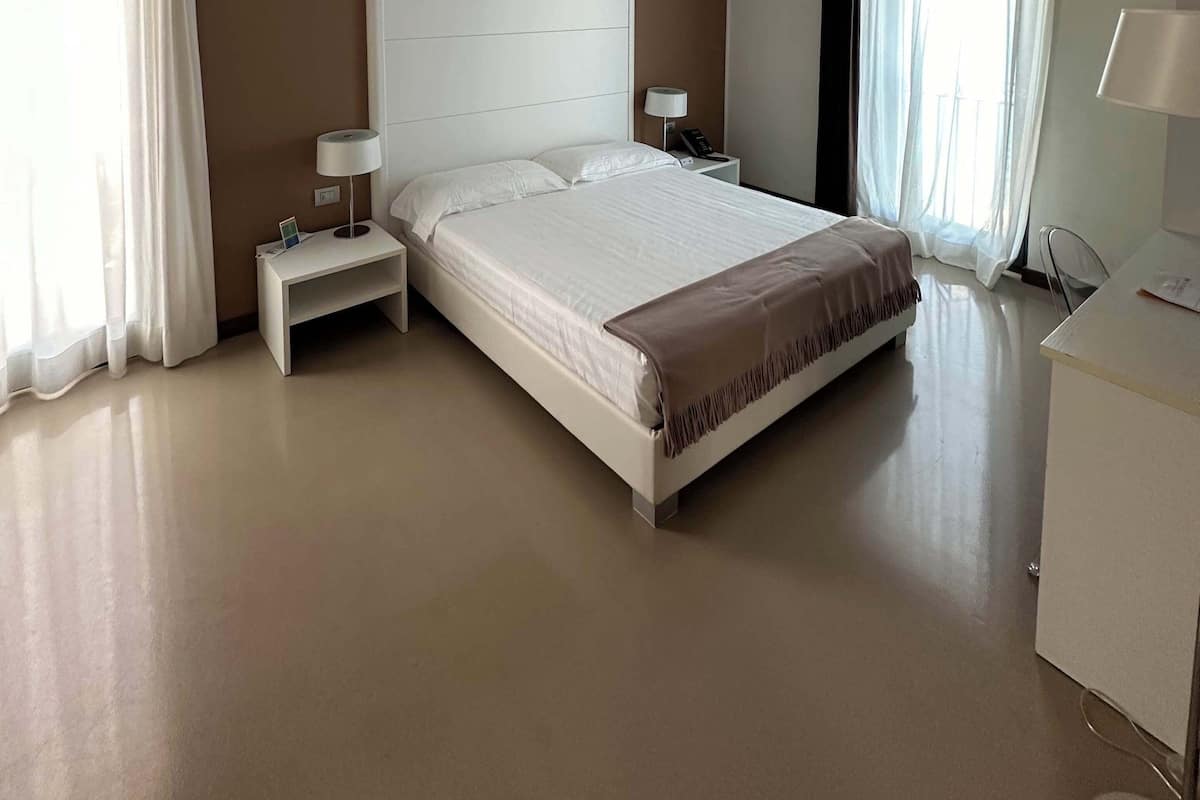 Una habitación de hotel moderna con una cama grande, mesitas de noche, un escritorio y cortinas.