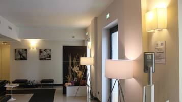 Eine moderne Hotelhalle mit Empfangstresen, Sitzgelegenheiten und Kunstwerken an den Wänden.
