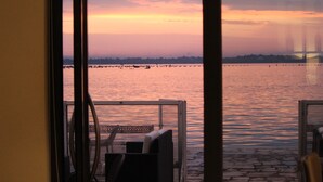Vista desde una habitación con ventana que da a un cuerpo de agua al atardecer.