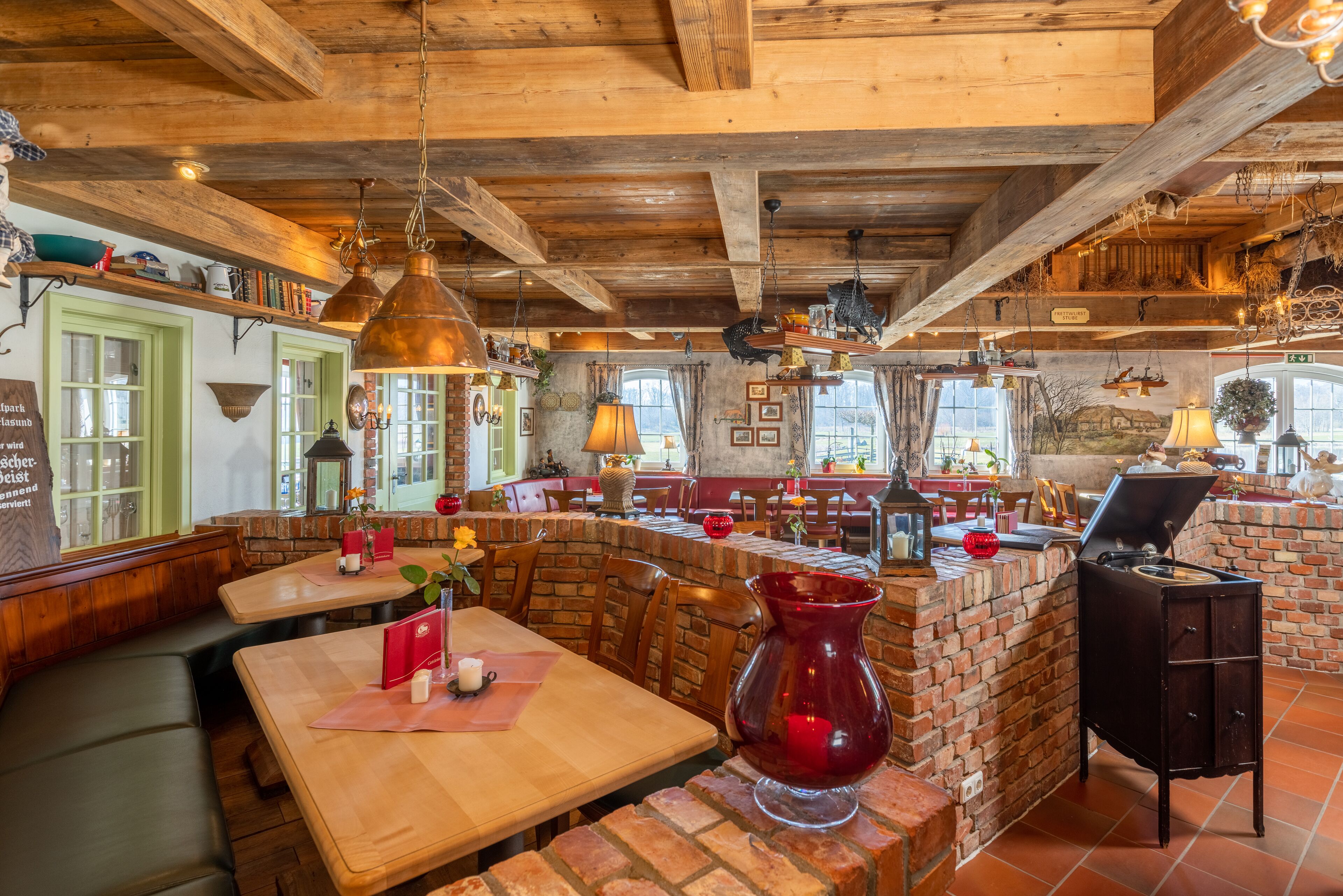 Ein rustikales Restaurant-Interieur mit Holzbalken, Backsteinwänden und verschiedenen Hängelampen.