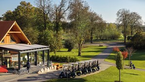 Un parcours de golf doté d’une réception et d’un magasin d’articles de golf, d’un chemin pavé et d’une rangée de voiturettes de golf.