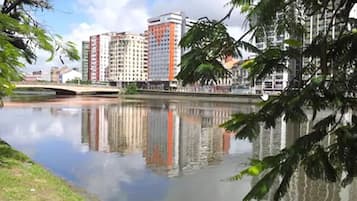Un río tranquilo con un puente al fondo, rodeado de edificios y árboles.