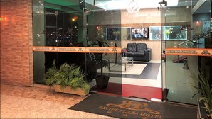 Vestíbulo de hotel con mostrador de recepción, zona de estar y pantalla de televisión.