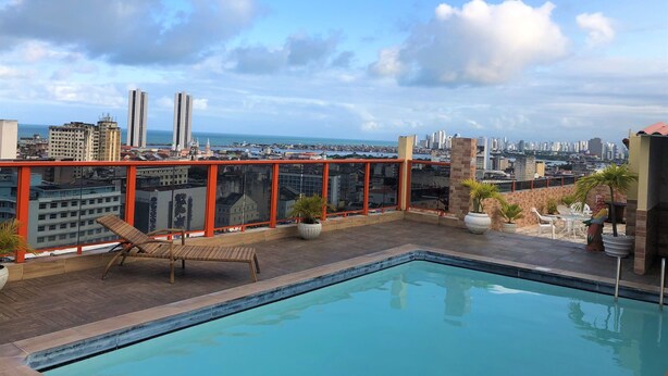 Una piscina en la azotea con vistas a la ciudad, incluyendo edificios altos y un cuerpo de agua.