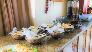 Una mesa de buffet con diferentes alimentos en cestas y un plato con sándwiches.