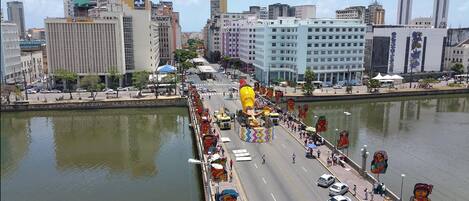 A cityscape with a river, buildings, and a bridge with colorful decorations.