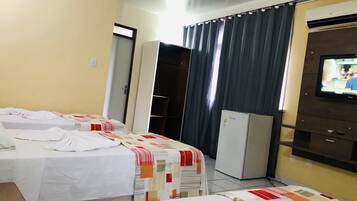 Una habitación de hotel con dos camas, televisión, refrigerador y armario.