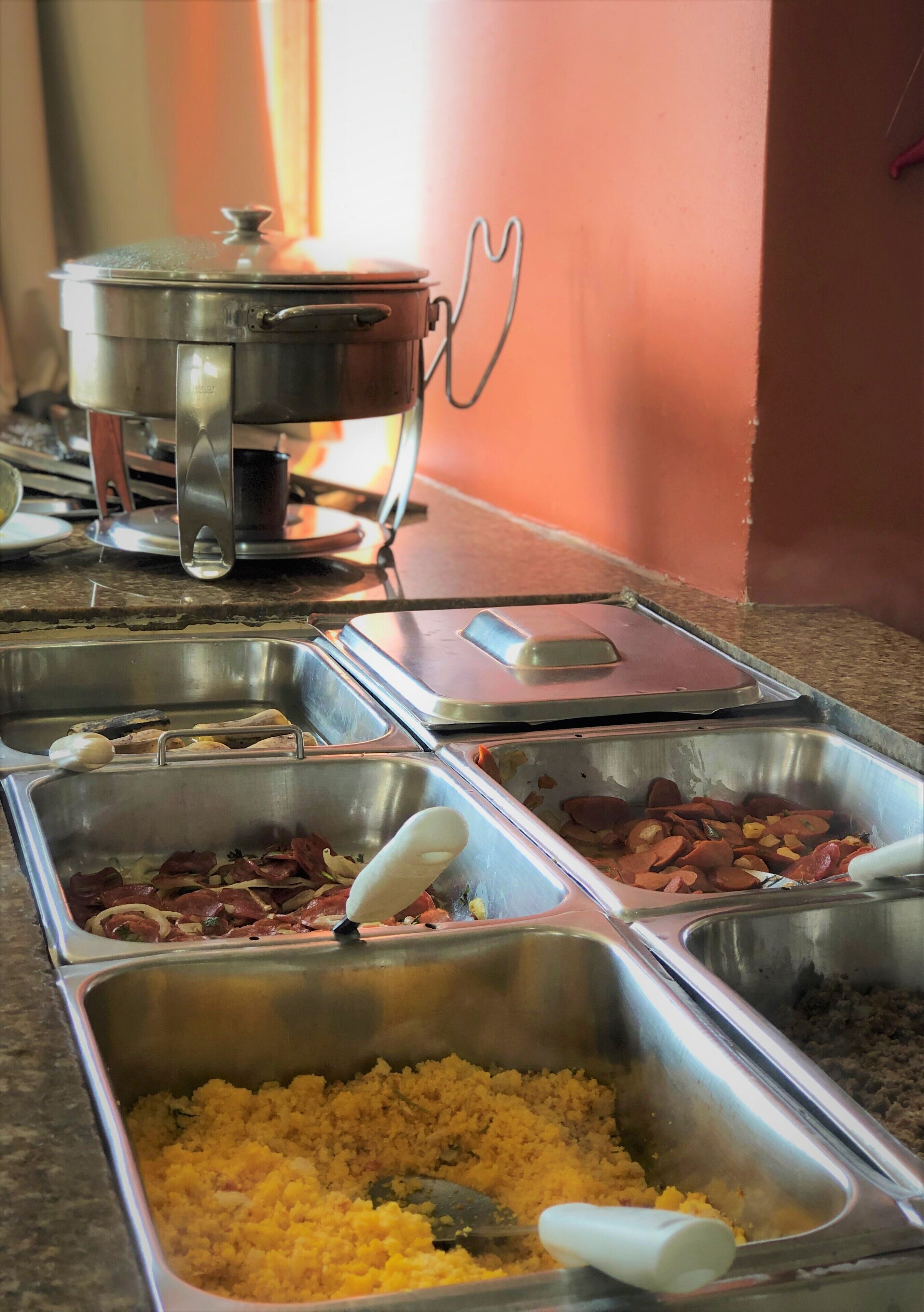 Un buffet con diversi piatti in vassoi metallici, tra cui carni e riso.