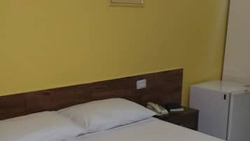 Una habitación de hotel con una cama, una mesita de noche, un teléfono y un refrigerador.
