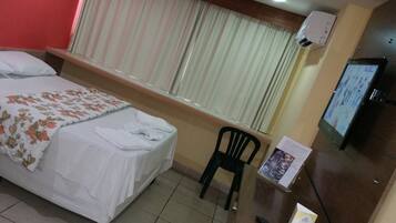 A hotel room with two beds, a desk with a chair, a television, and a window with curtains.