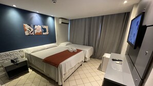 Habitación de hotel con dos camas, televisión, escritorio y baño.