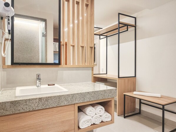 A modern bathroom with a granite countertop sink, wooden vanity, and a mirror above the sink.