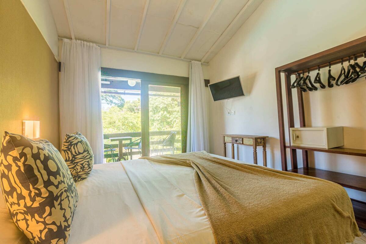 A bedroom with a bed, a television mounted on the wall, and a window with curtains.
