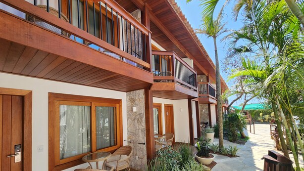 A two-story building with a balcony, a patio with wicker furniture, and a stone pathway. - Blu Smart Stay (Búzios)