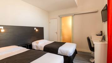 A hotel room with two beds, a desk, a chair, and a TV.