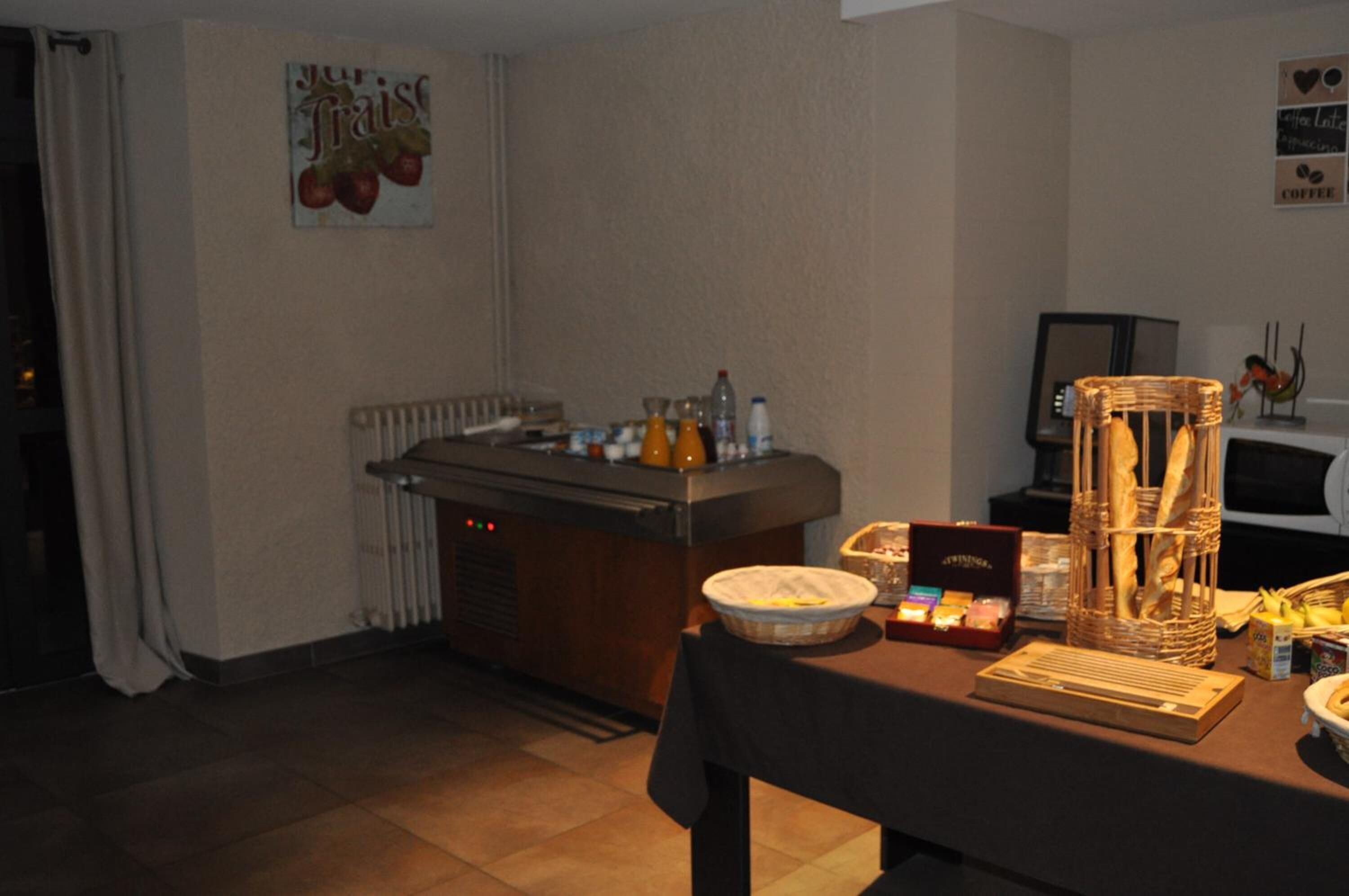 Een keuken met een inbouwfornuis, een tafel met broodmanden en een koelkast.