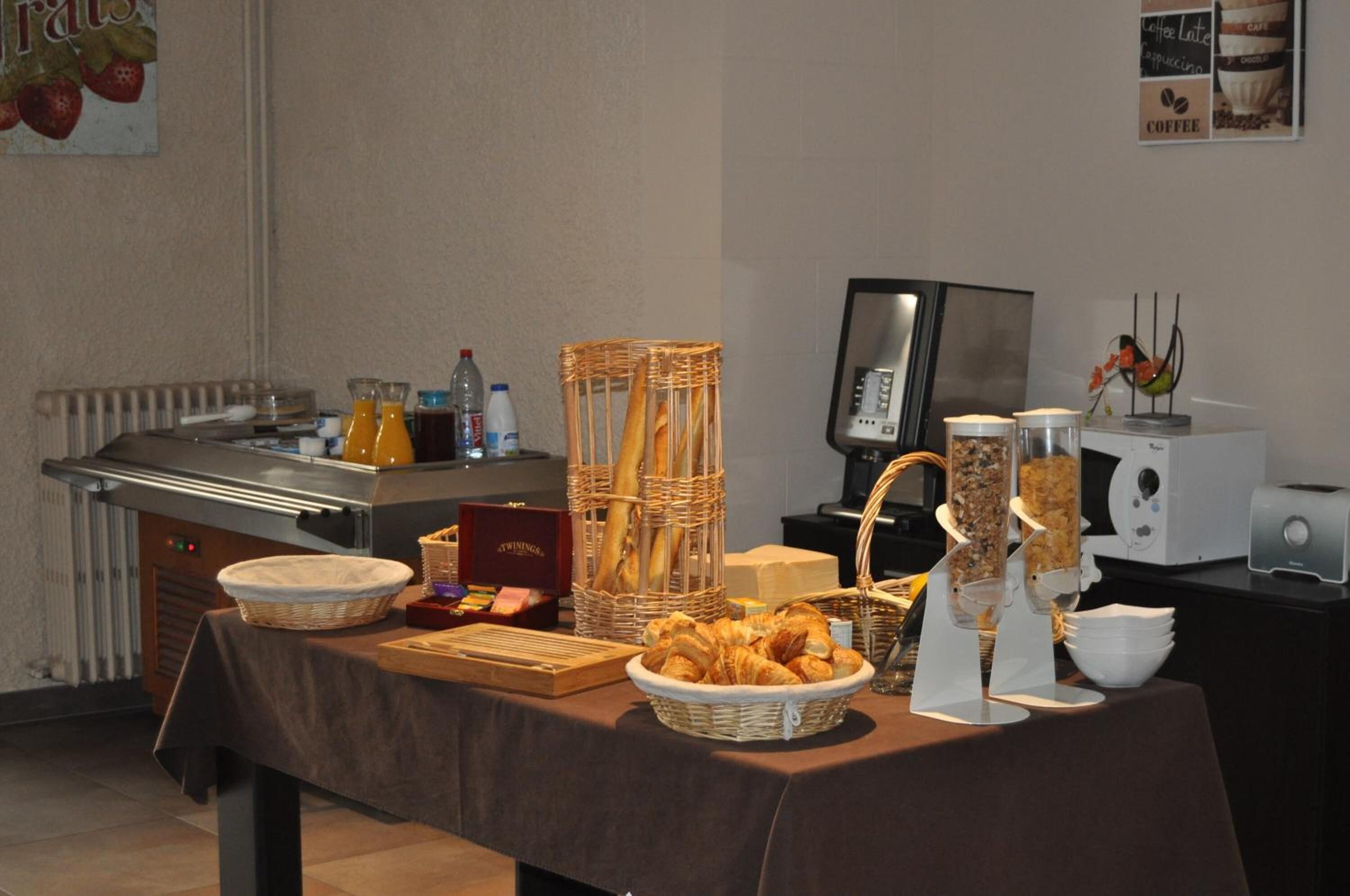 A buffet setup with various food items, including bread, pastries, and beverages.