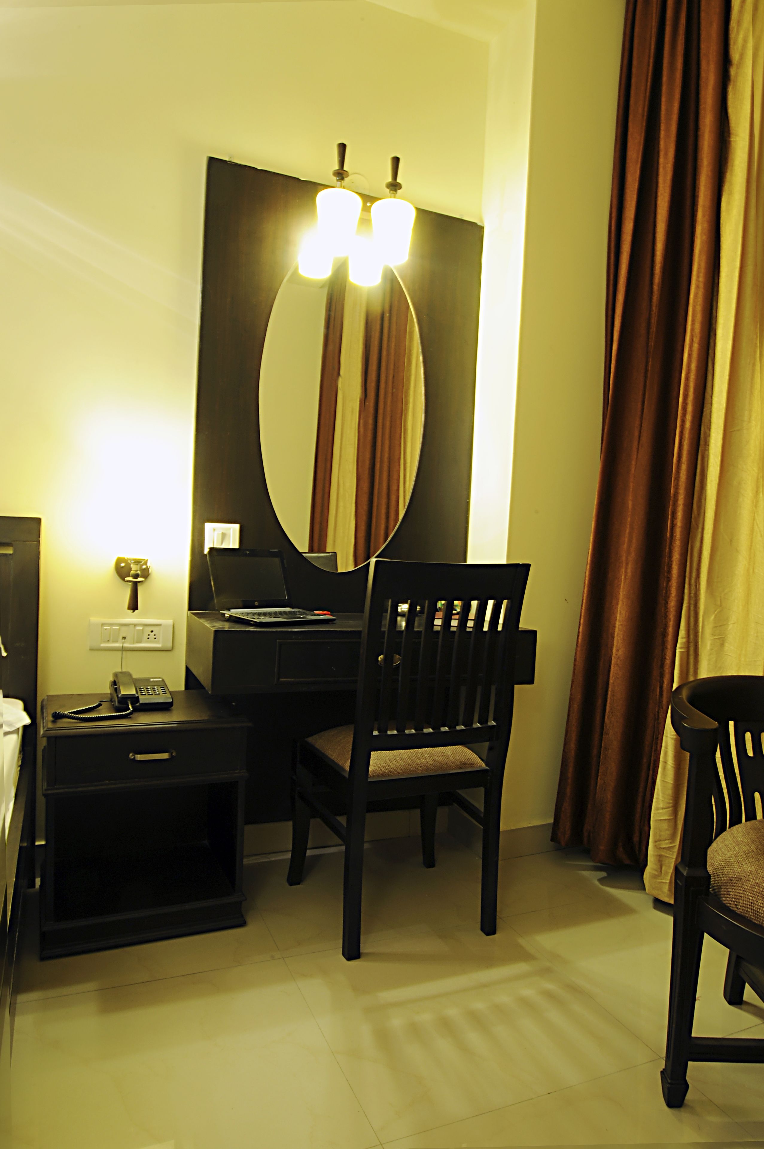 Habitación de hotel con escritorio, silla y un espejo grande.