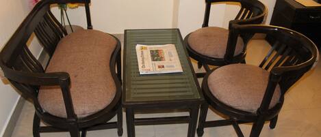 A dining area with a table and four chairs, a newspaper on the table, and a vase of flowers on the wall.