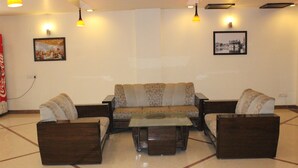 A living room with a sofa set, a coffee table, and pendant lighting. - Hotel Hong Kong Inn (Amritsar)