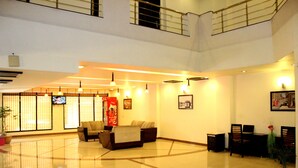 A spacious lobby with a high ceiling, a seating area with sofas, a television, and a traditional Japanese screen. - Hotel Hong Kong Inn (Amritsar)