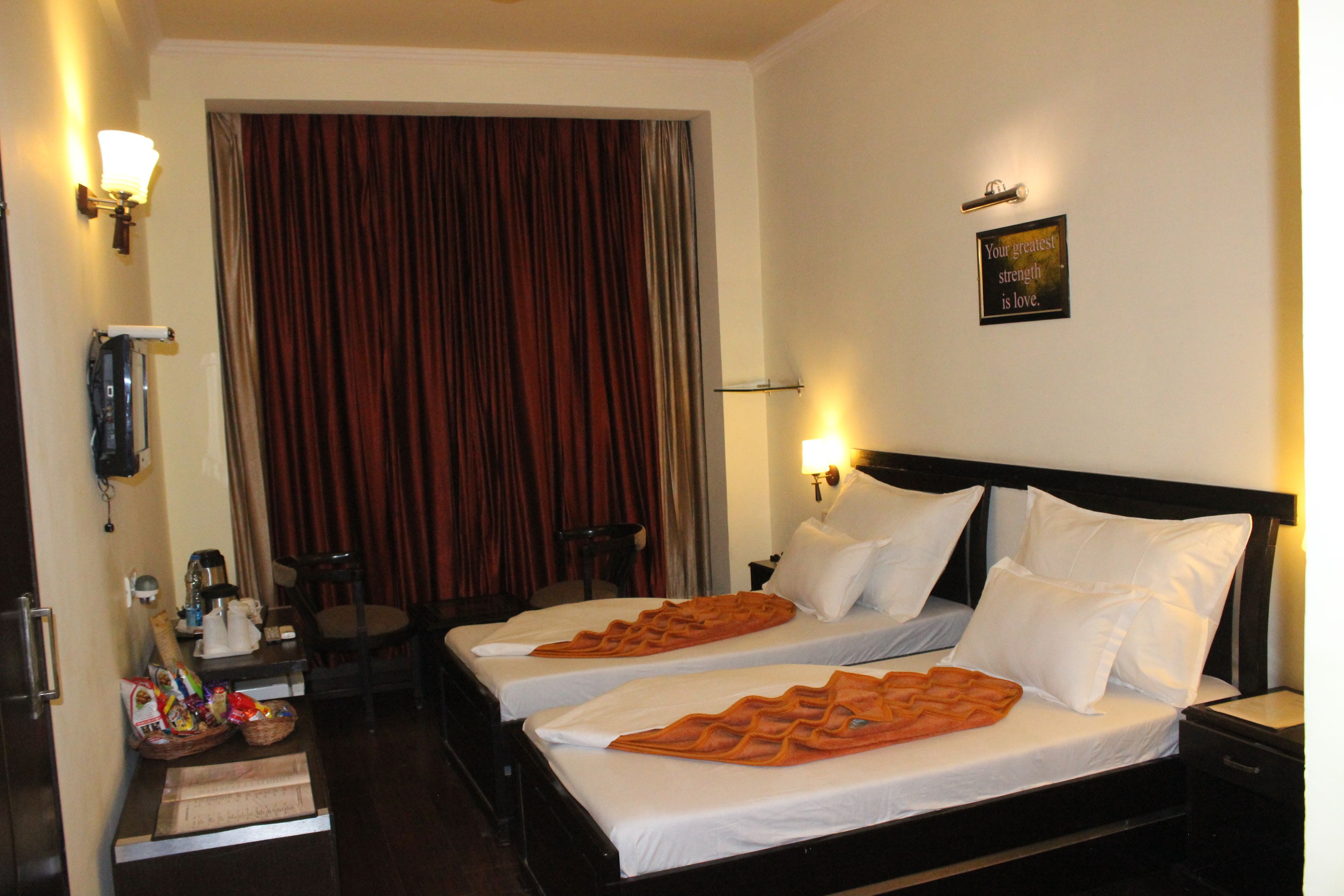 Habitación de hotel con dos camas, un escritorio, una silla y una cortina.