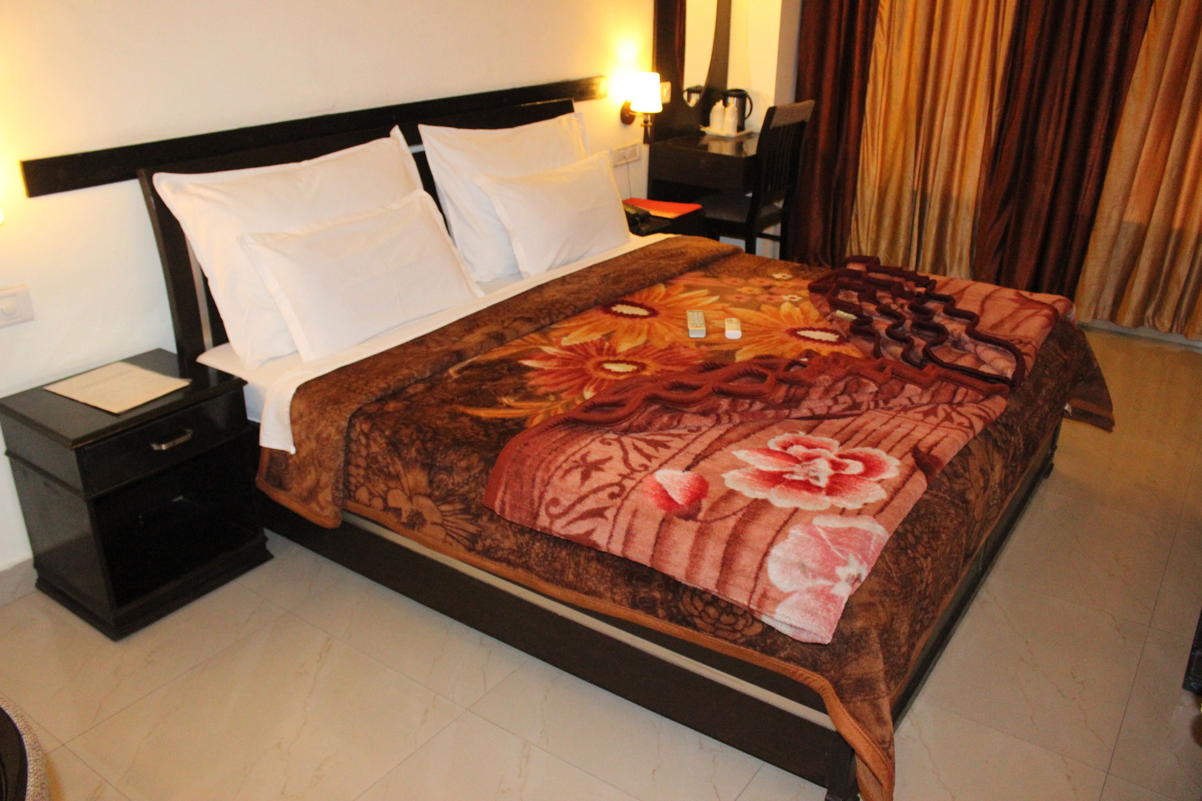 Une chambre d’hôtel avec un lit, une table de chevet, un bureau et une chaise.