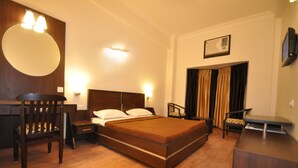 A hotel room with a large bed, wooden furniture, a desk, and a chair. - Hotel Hong Kong Inn (Amritsar)