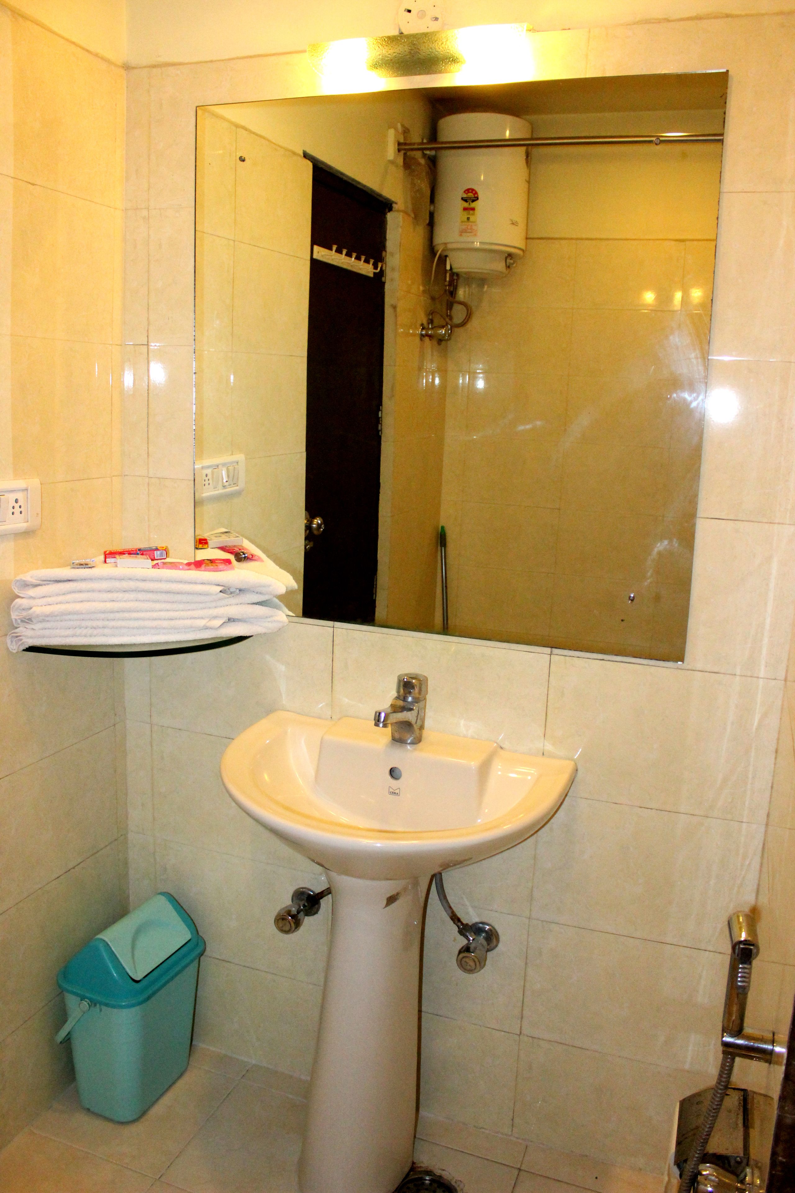 A bathroom with a sink, mirror, towel rack, and a trash bin.