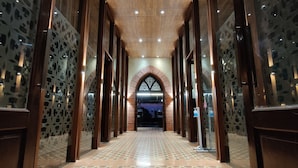 A hallway with patterned floor tiles, wooden paneling, and a central arched doorway. - Regenta MPG Club (Mahabaleshwar)