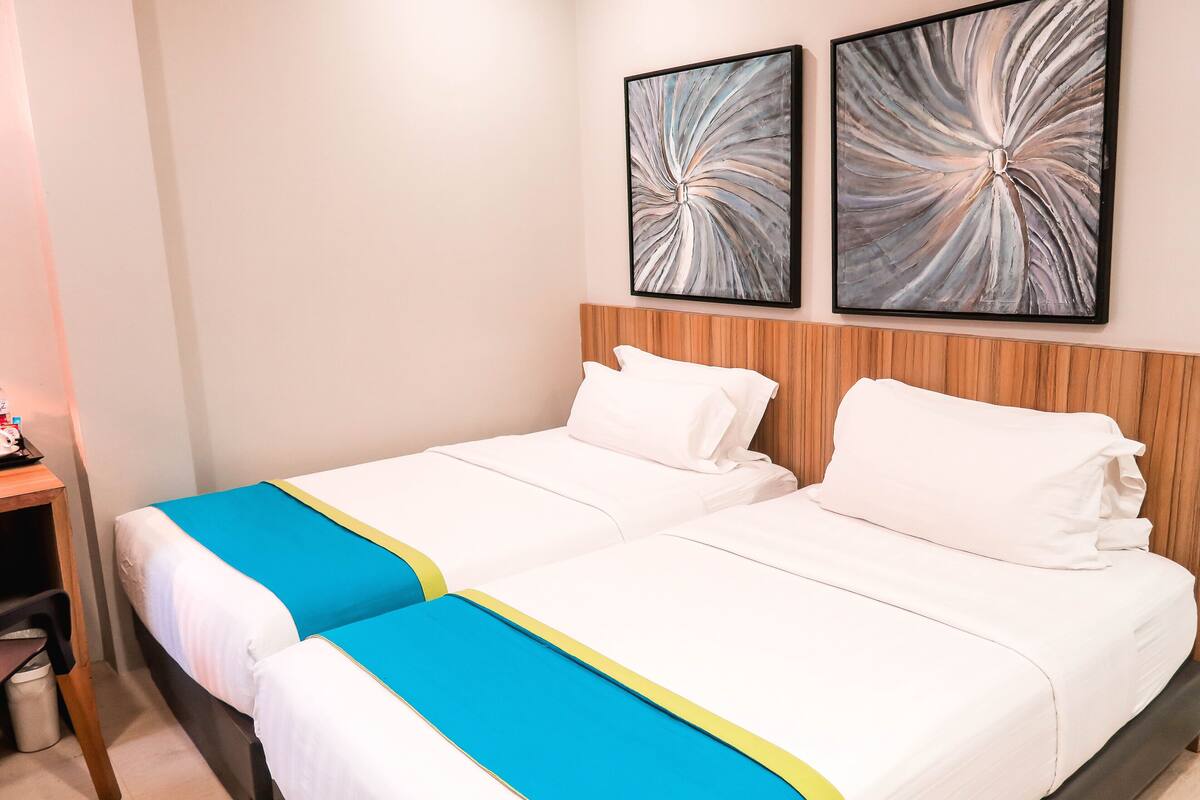 A double bed with white bedding and a blue and yellow accent.