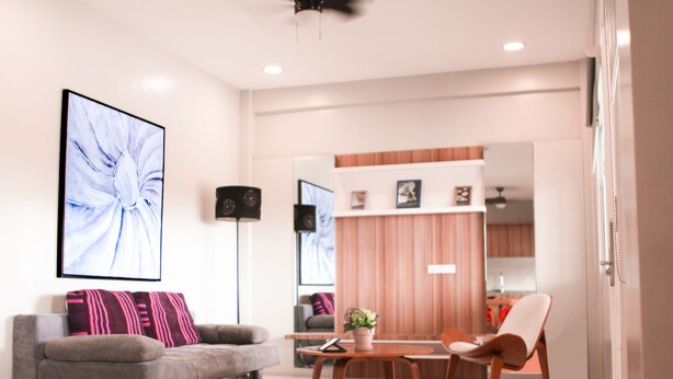 A modern living room with a grey sofa, a wooden coffee table, and a white armchair. - Zpad Residences (Tacloban)