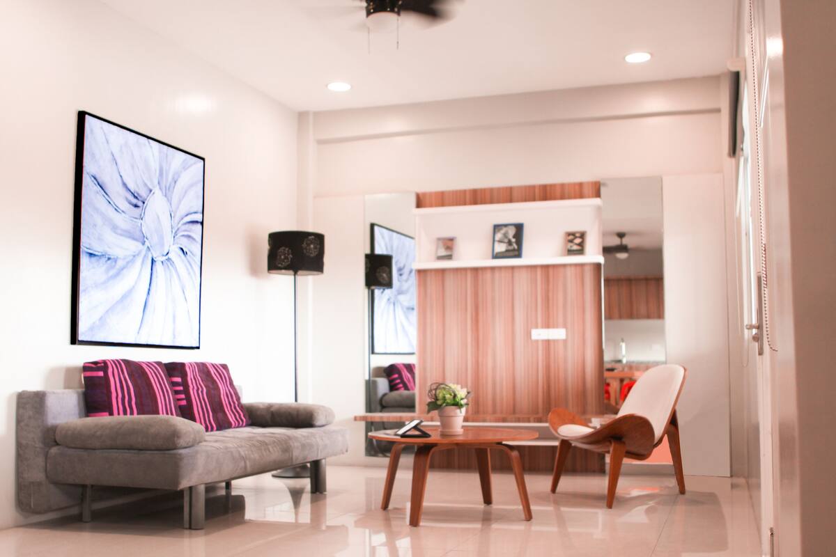 A modern living room with a grey sofa, a wooden coffee table, and a white armchair.
