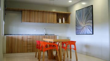 Una cocina moderna con armarios de madera, encimera de granito y comedor con mesa de madera y sillas color naranja.
