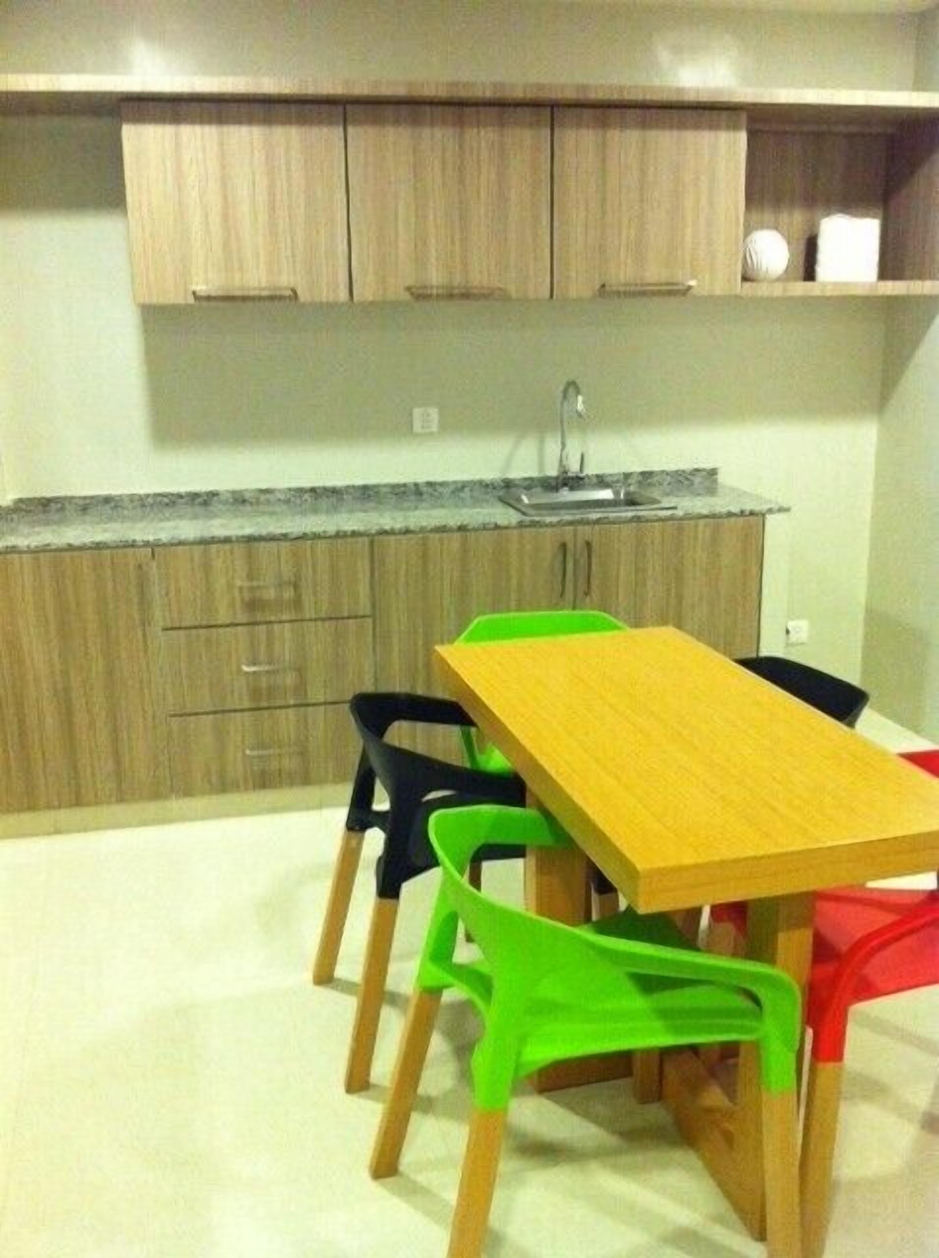 Una cocina pequeña con armarios de madera, un lavamanos y una mesa con sillas.