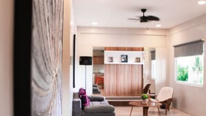 A modern living room with a grey sofa, a small round table, and a ceiling fan. - Zpad Residences (Tacloban)
