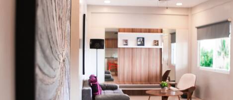 Ein modernes Wohnzimmer mit grauem Sofa, einem kleinen runden Tisch und einem Deckenventilator.