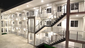 A multi-story hotel with a central staircase, balconies, and a green area at the base. - Zpad Residences (Tacloban)