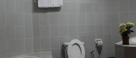 A bathroom with a bathtub, toilet, and a small potted plant.