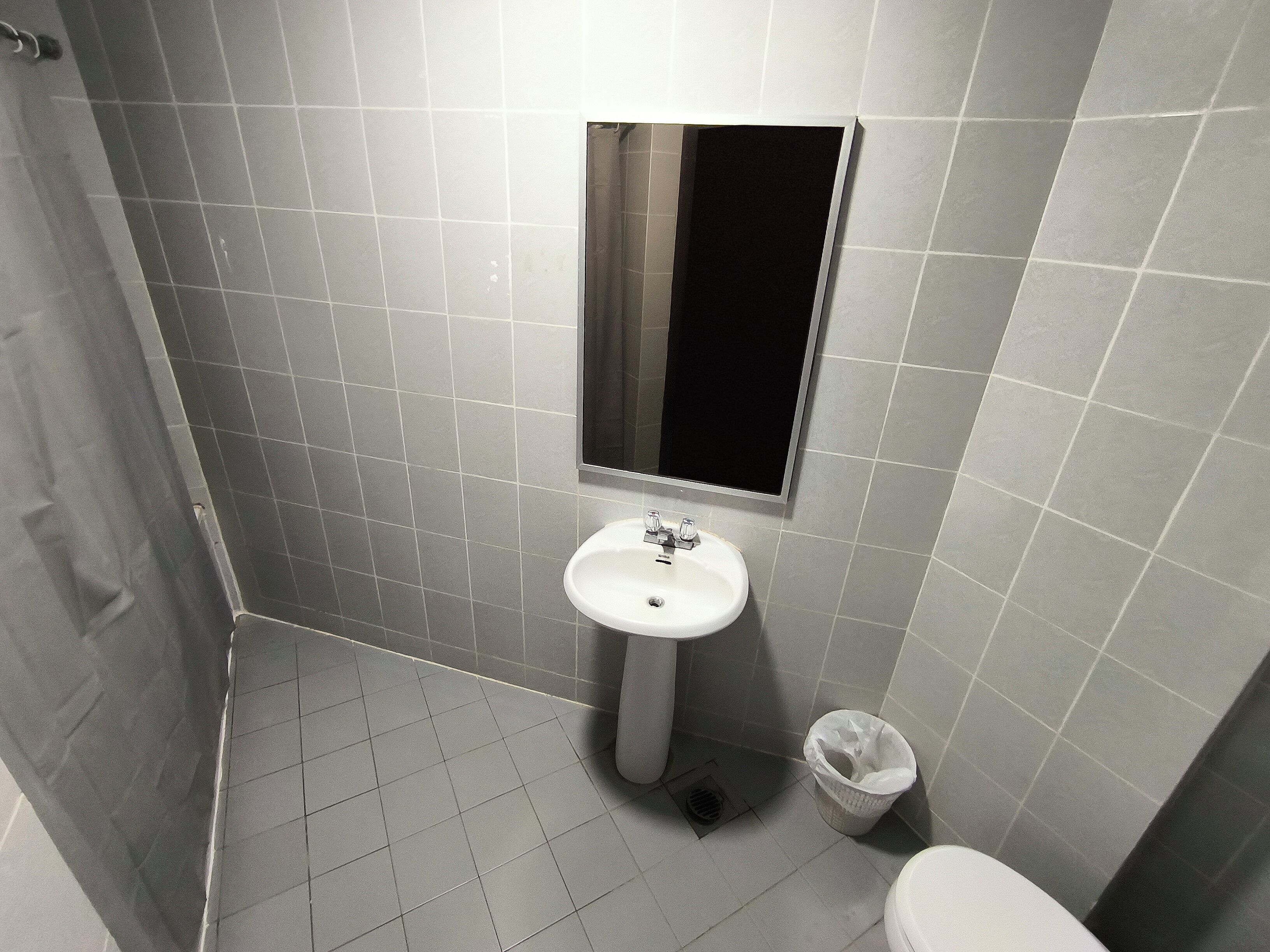 Ein kleines Badezimmer mit einem weißen Waschbecken, einem Spiegel und einer Toilette.