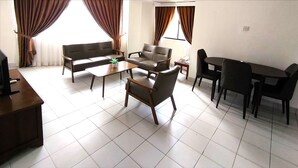 A living room with a sofa, chairs, a coffee table, and a dining table. - Jubilee Hotel (Bandar Seri Begawan)