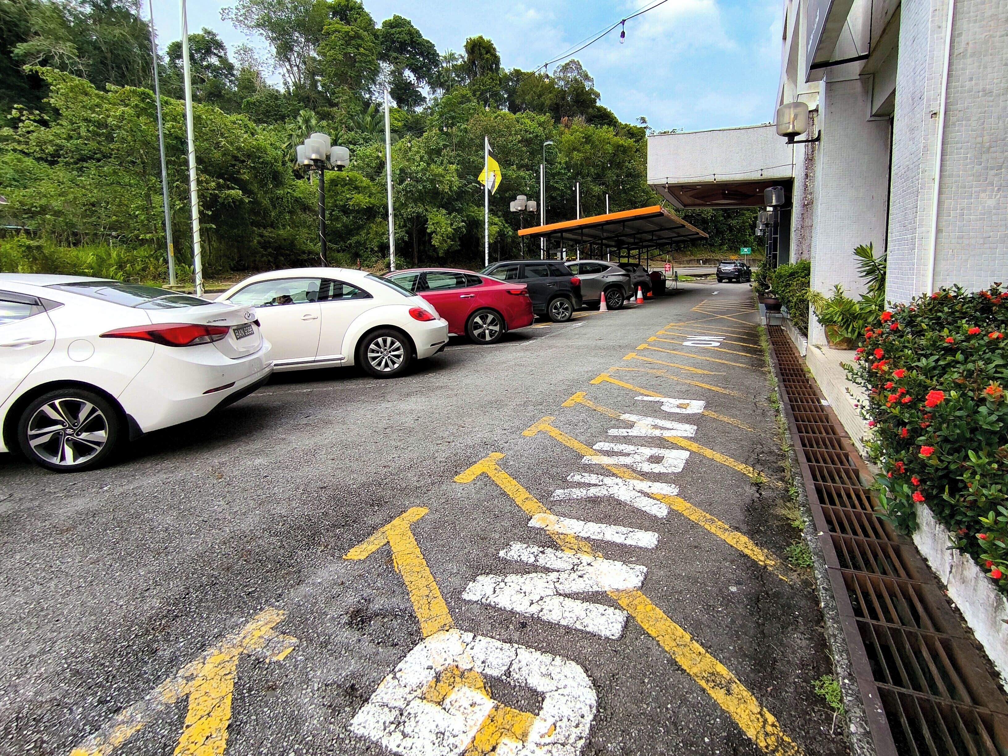 Un estacionamiento con espacios delimitados y un edificio de fachada con tejas.