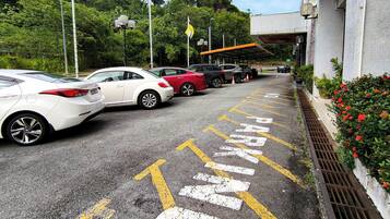 Un estacionamiento con espacios delimitados y un edificio de fachada con tejas.