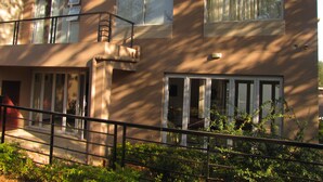 A multi-story building with large windows, a visible air conditioning unit, and a metal railing in the foreground.