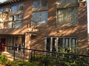 A multi-story building with large windows, a visible air conditioning unit, and a metal railing in the foreground.