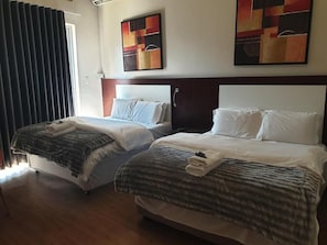A hotel room with two beds, a wooden headboard, and abstract wall art.