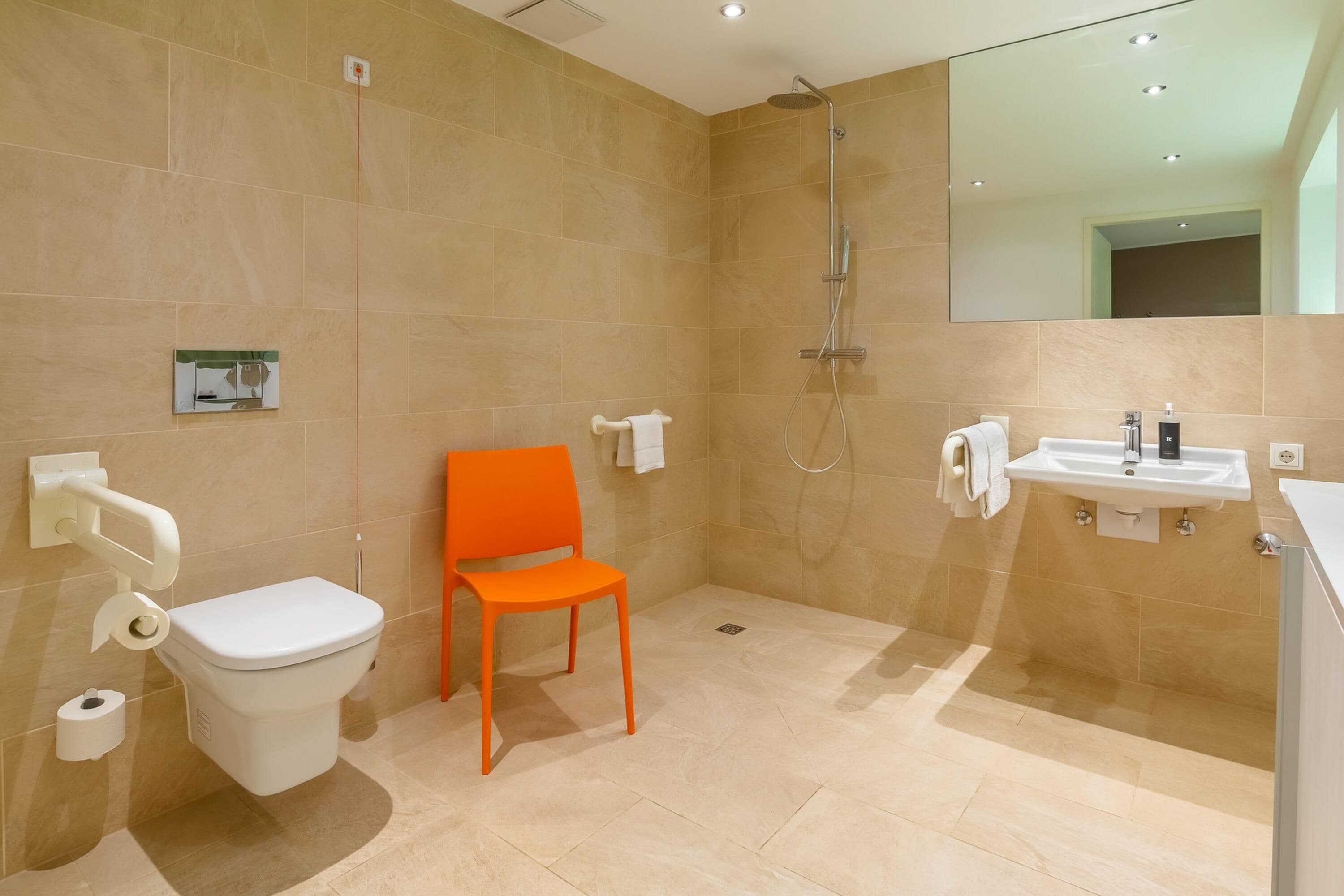 Une salle de bain moderne équipée de toilettes, d’une douche, d’un lavabo et d’une chaise.
