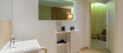 A hotel bathroom with a sink, mirror, towel rack, and a shelf with toiletries.