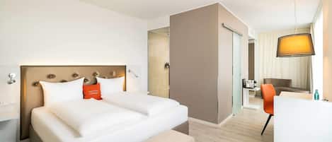 A hotel room with a large bed, a desk, and a chair.