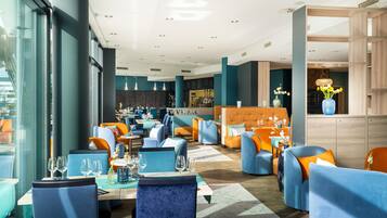 Un restaurante moderno con asientos azules y naranjas, una zona de bar y un menú a la vista.